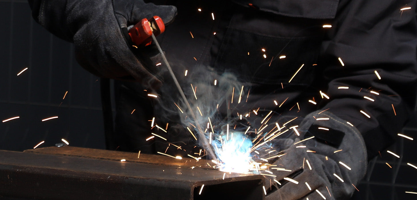 Close-up of welder using stick welder with sparks and protective gloves