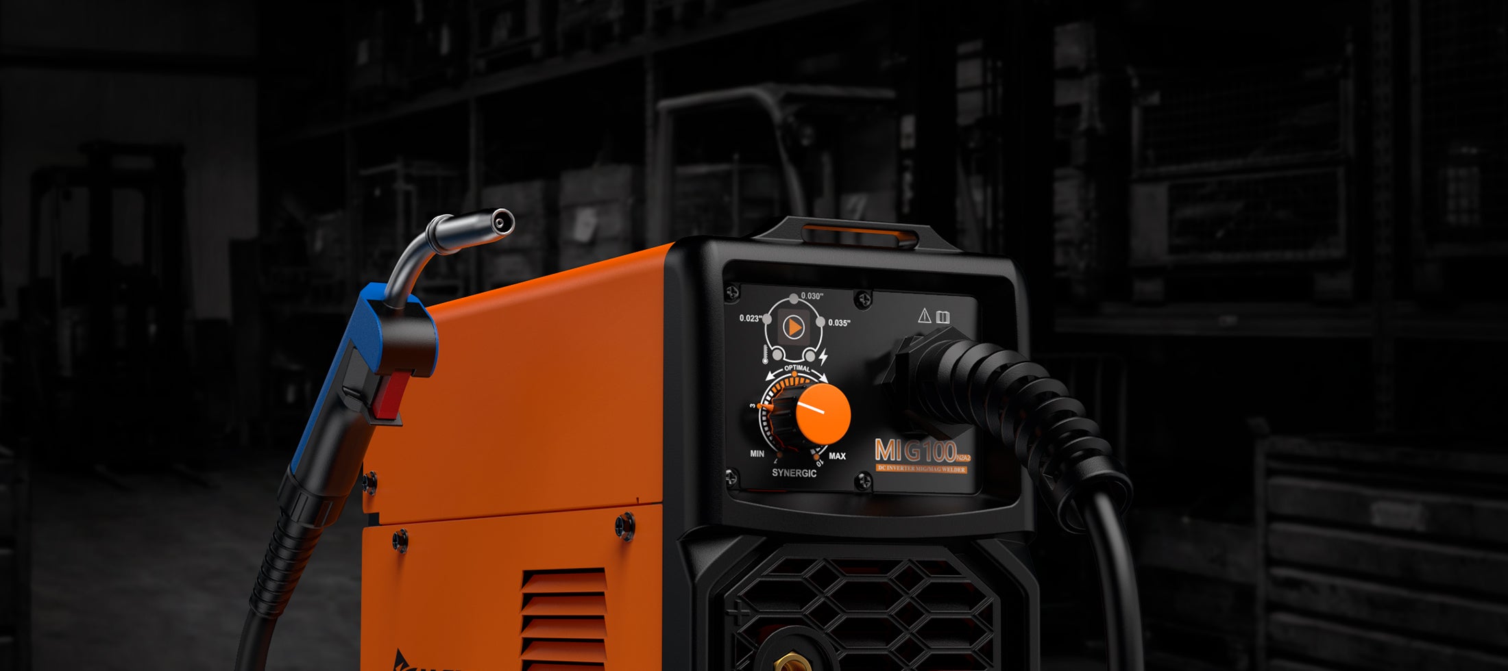 Close-up of orange MIG100 industrial MIG welder with wire feed gun in workshop setting